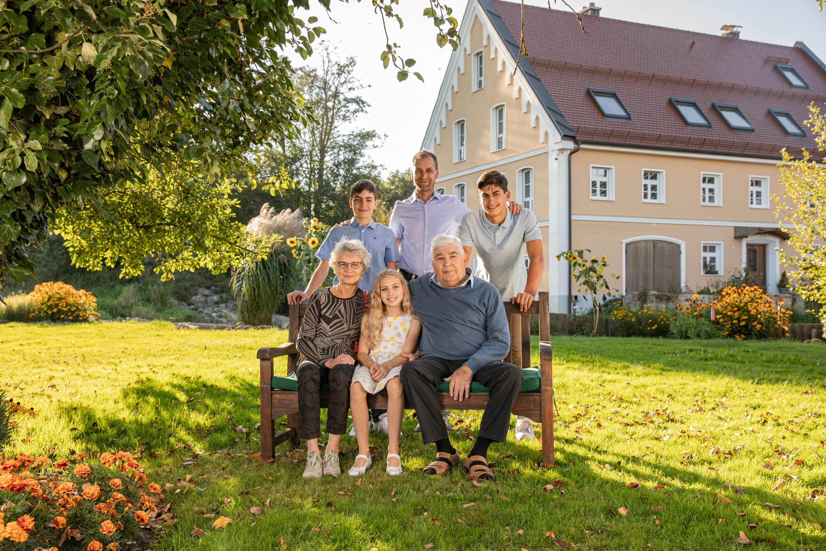 Familien Bild von Welzhofer in einem sonnigen Garten vor einem Haus